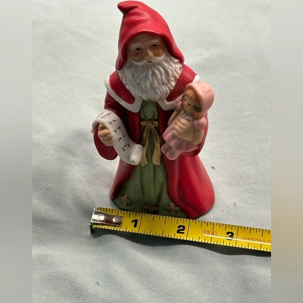 Small porcelain Santa figure.Santa carries a doll and a copy of his list.